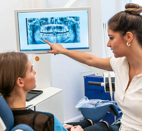 Bild von einer Zahnärztin die einer Patientin, ein Röntgenbild erklärt.