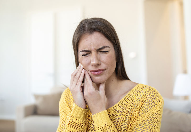 Frau hält schmerzversehrt Ihre Wange