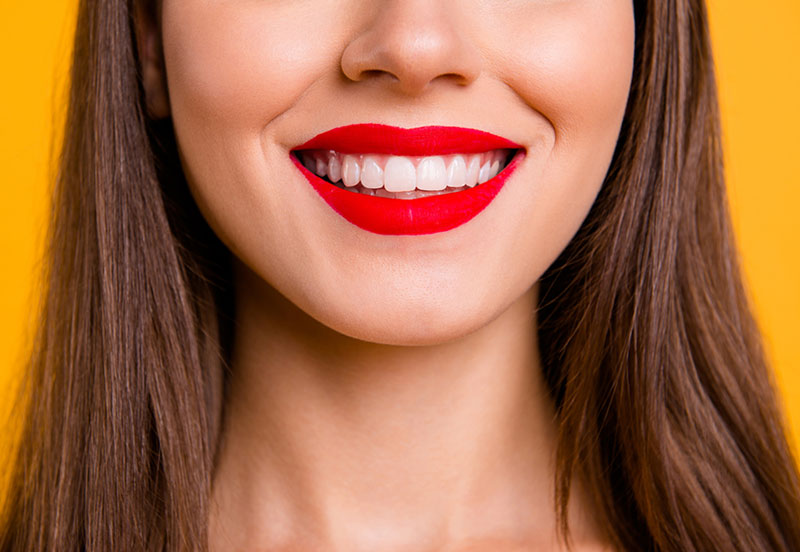 Frau lächelt mit roten Lippenstift und sauberen weißen Zähnen